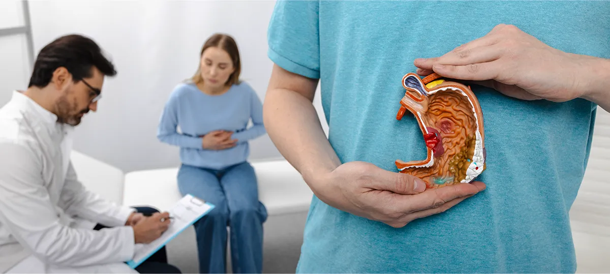 Liječnik, pacijentica i osoba s anatomskim modelom želuca; koncept živjeti s gastritisom