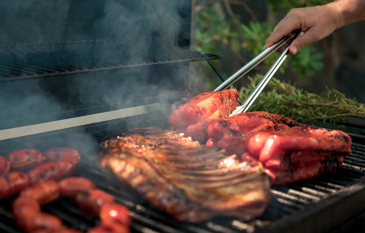 Priprema crvenog mesa i kobasica na roštilju; koncept živjeti s gastritisom
