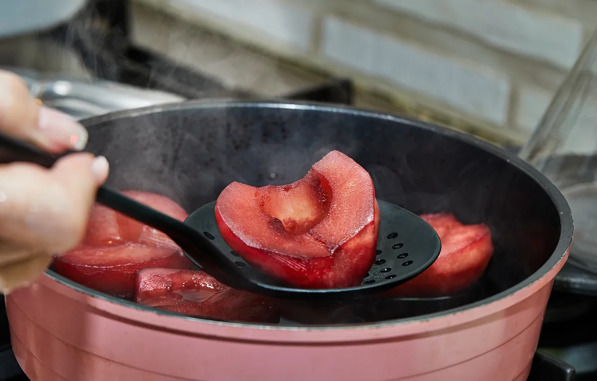 Osoba vadi kuhano voće iz lonca; koncept živjeti s gastritisom