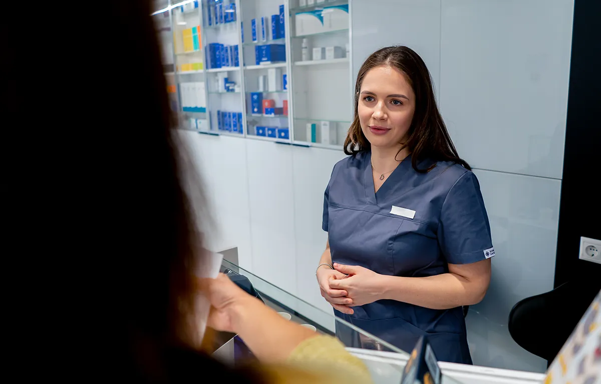 Farmaceutkinja u ljekrani razgovara s pacijenticom vidljivu s leđa; koncept galenski i magistralni pripravci