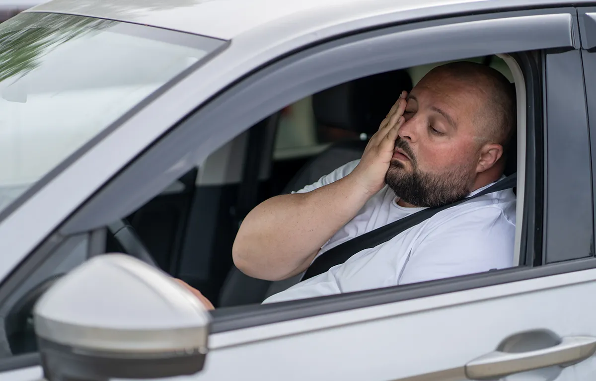 Umoran muškarac u automobilu; koncept kava i kofein