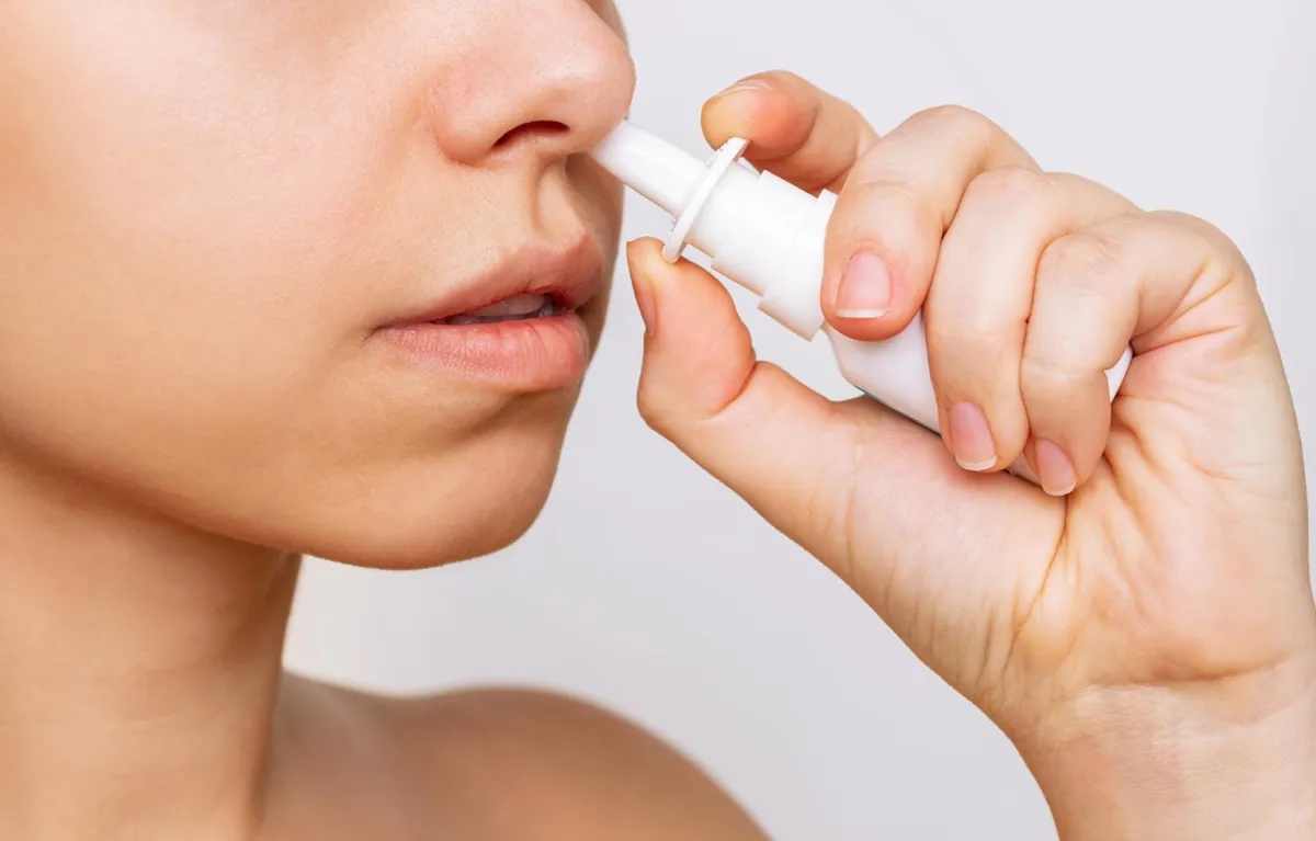 sprej-cjepivo-gripa Žena drži cjepivo protiv gripe u spreju na vrhu nosnice; koncept cjepivo protiv gripe u spreju