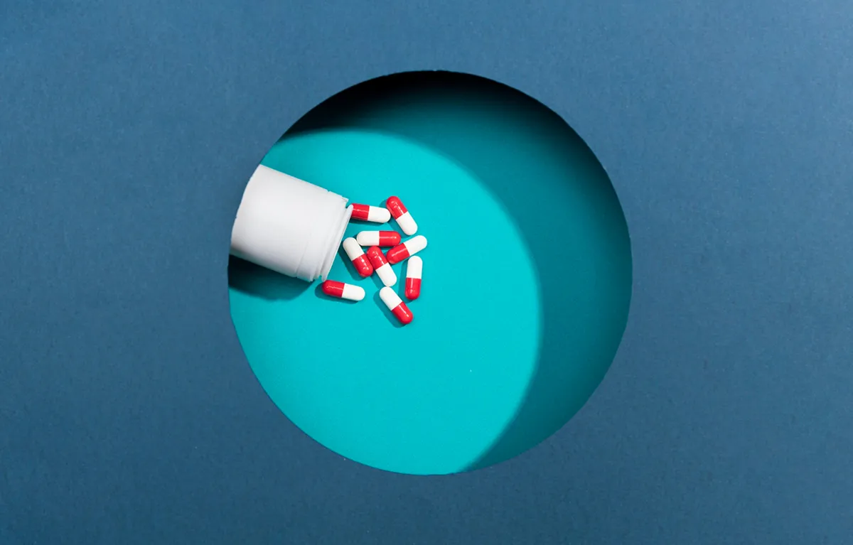 veledrogerije-dugovi Crvene i bijele tablete iza papirnatog kruga; koncept dugovi za lijekove