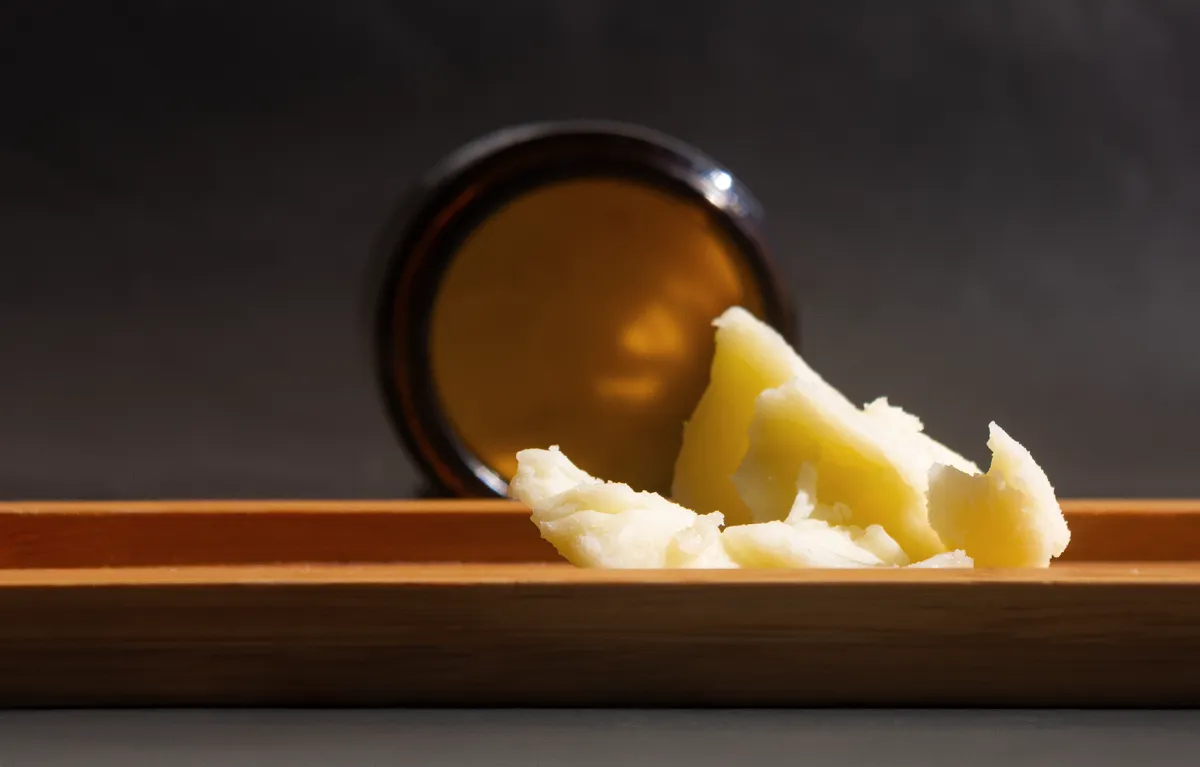 Tallow, krema za lice od goveđe masti na drvenoj podlozi i posuda za kremu u pozadini