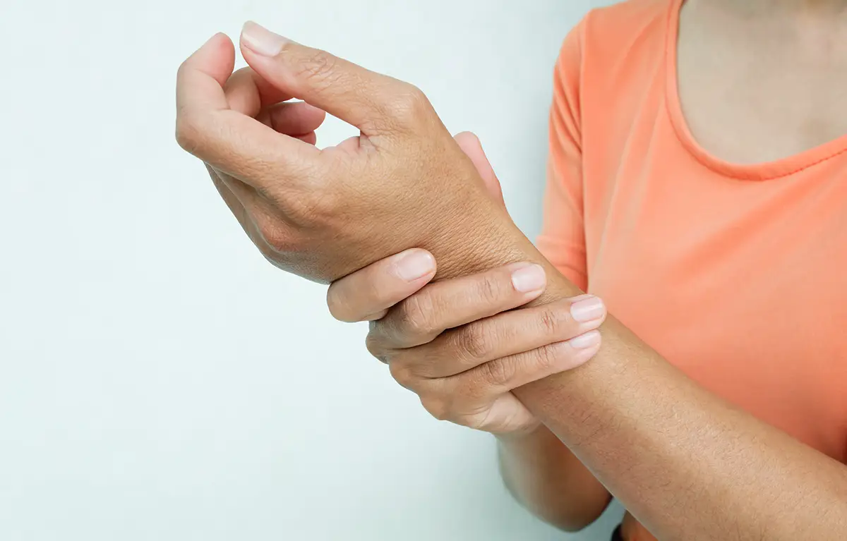 Krupni plan, neprepoznatljiva žena drži se za bolni zglob ruke; tema artralgije bolni zglobovi kod liječenja raka