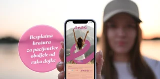 Mlada žena u zalasku sunca pokazuje mobitel prema kameri s prikazom besplatne brošure ENEA Klinike za tumore KBC-a Rijeka.