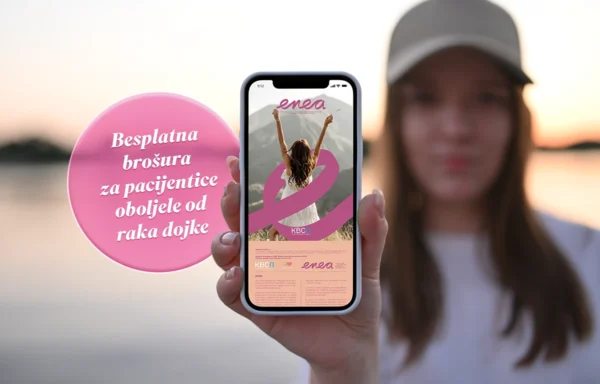 Mlada žena u zalasku sunca pokazuje mobitel prema kameri s prikazom besplatne brošure ENEA Klinike za tumore KBC-a Rijeka.