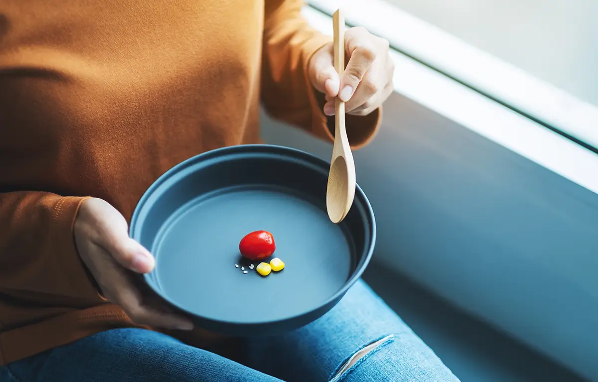 Neprepoznatljiva žena na tanjuru ima samo par komadića hrane, kao primjer loše restriktivne dijete; prehrana kod raka dojke