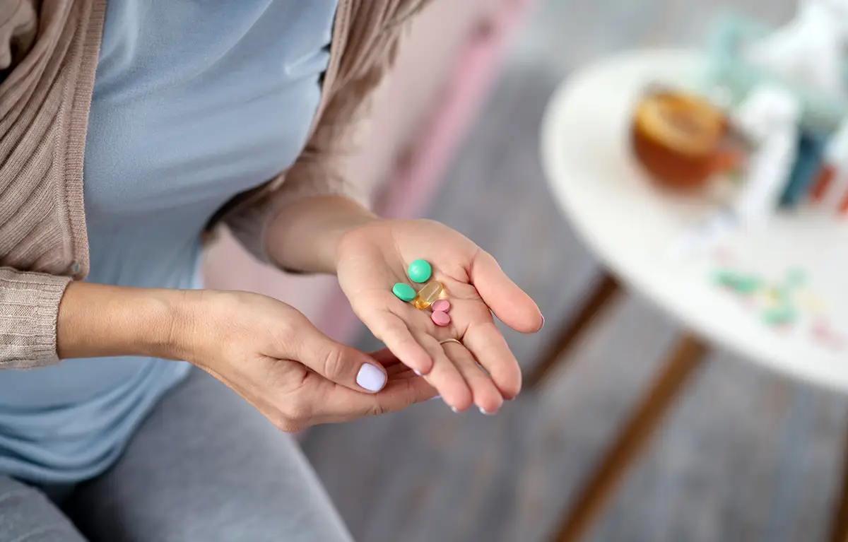 Neprepoznatljiva žena u ruci drži različite tablete; interakcija lijekova