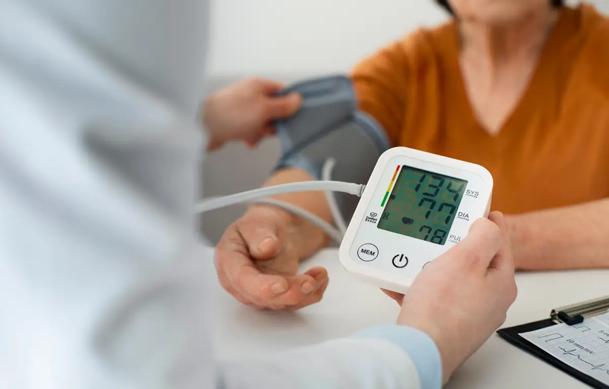 Liječnik pacijentici mjeri povišeni krvni tlak, rezultat visokog tlaka prikazan je na tlakomjeru.