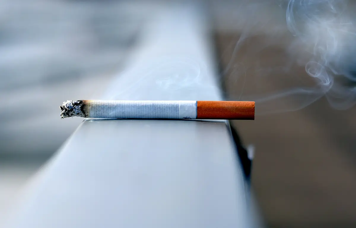 Upaljena cigareta na ogradi, u krupnom planu