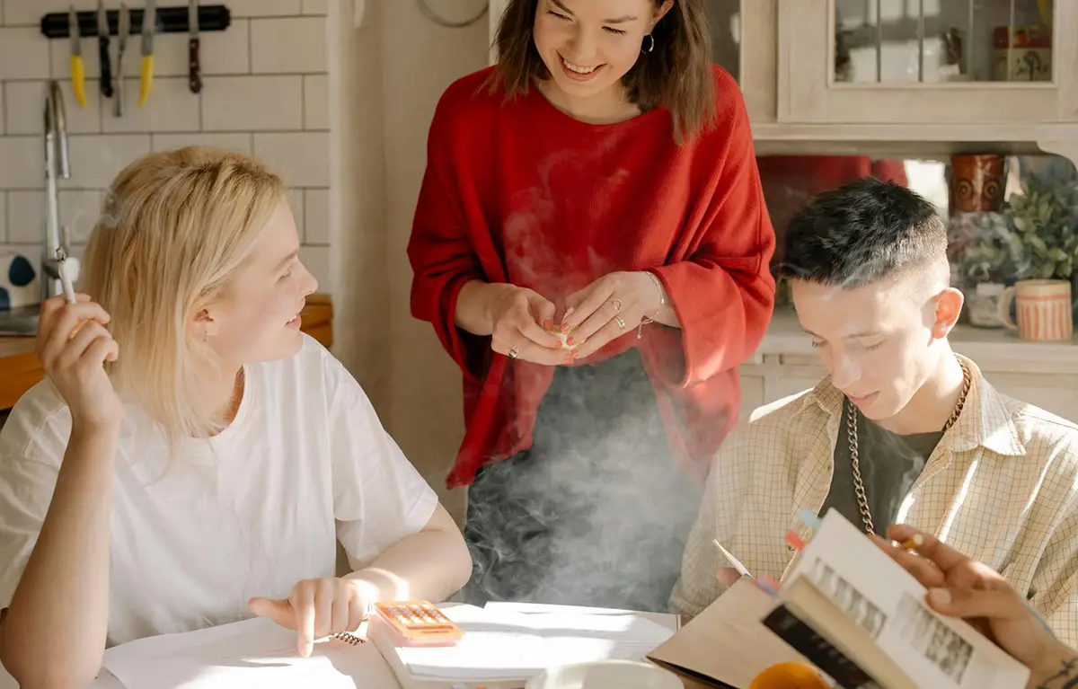 Skupina mladih u prostoriji od kojih jedna osoba puši cigaretu