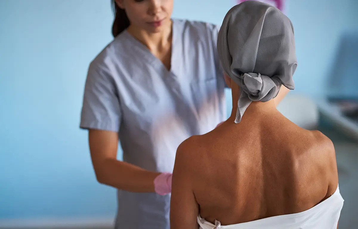 Pacijentica prikazana s leđa tijekom liječenja raka dojke na pregledu kod liječnika; poremećaji kose kože i noktiju kod liječenja raka dojke.