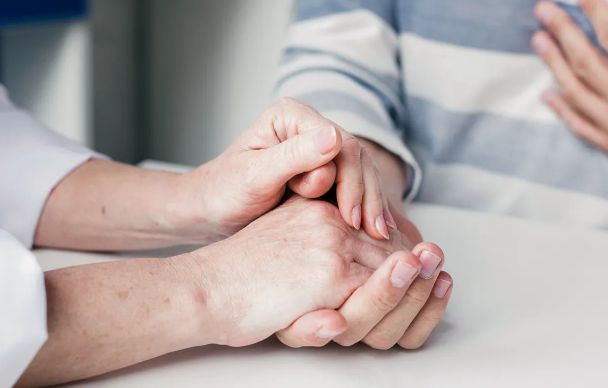 Čvrst stisak ruku dviju ženski osoba u krupnom planu; tekst Ljiljana Koci, podrška pjesnika oboljelima od raka.