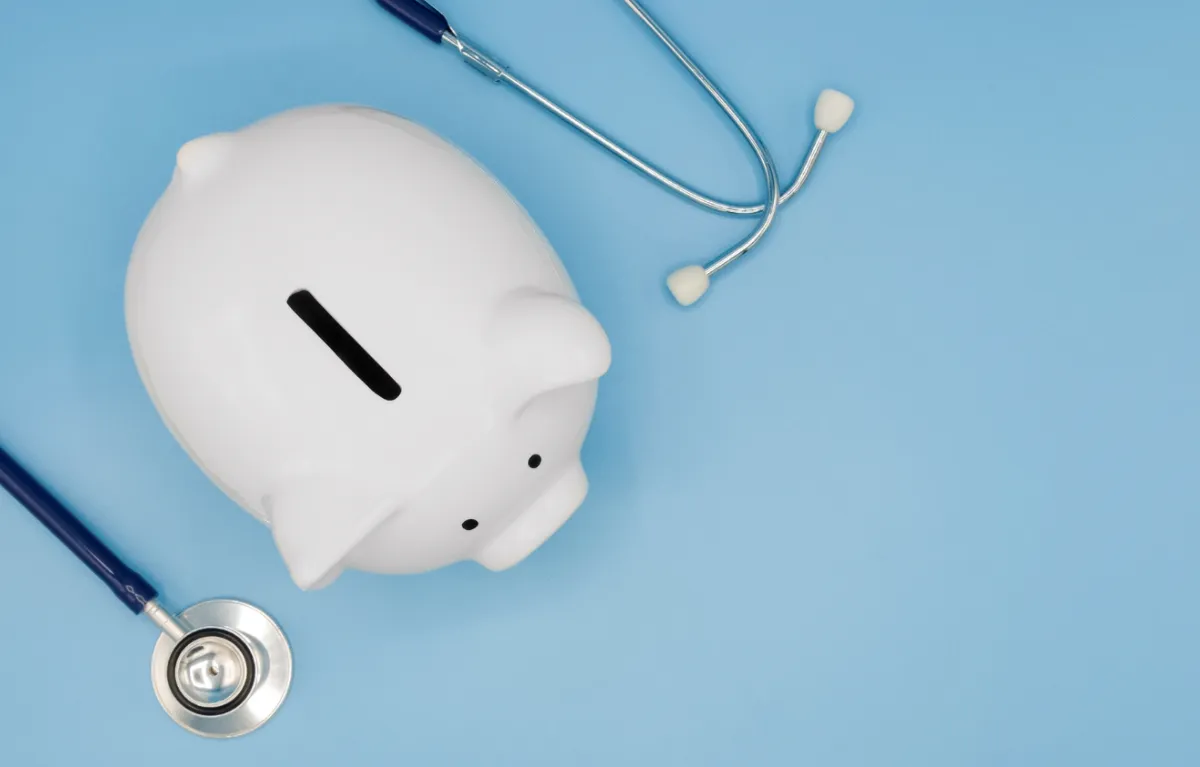 Bijela kasica prasica i stetoskop na plavoj pozadini; koncept ulaganje u zdravstvo