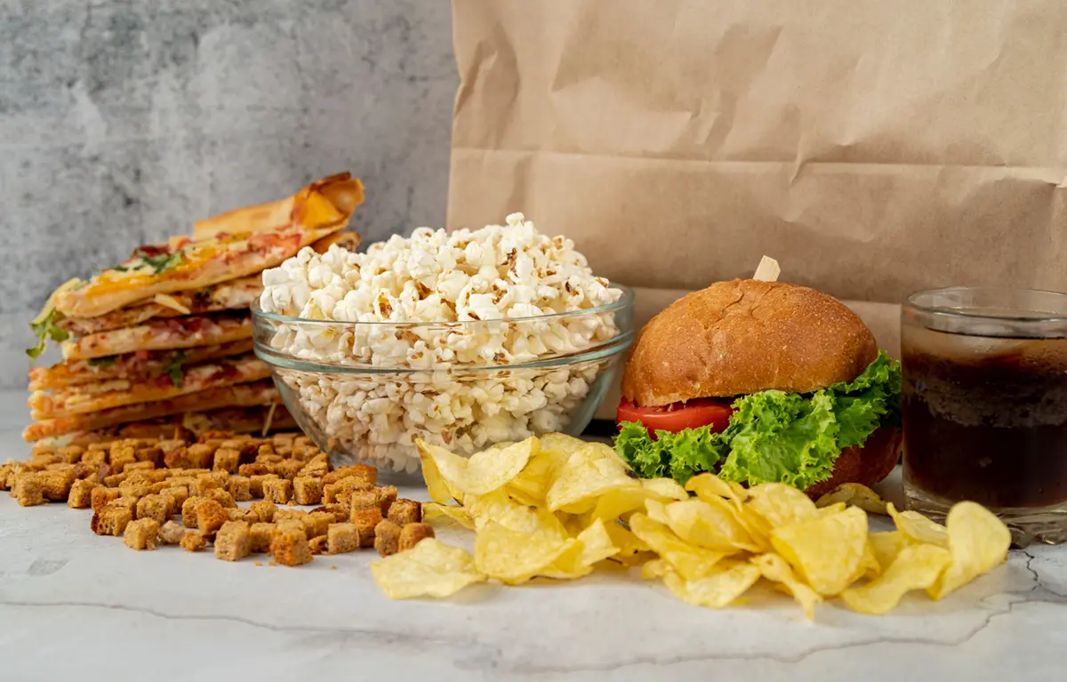 ultrapreradjena-hrana Kokice, hamburger i čips na stolu, primjeri za ultra prerađena hrana.