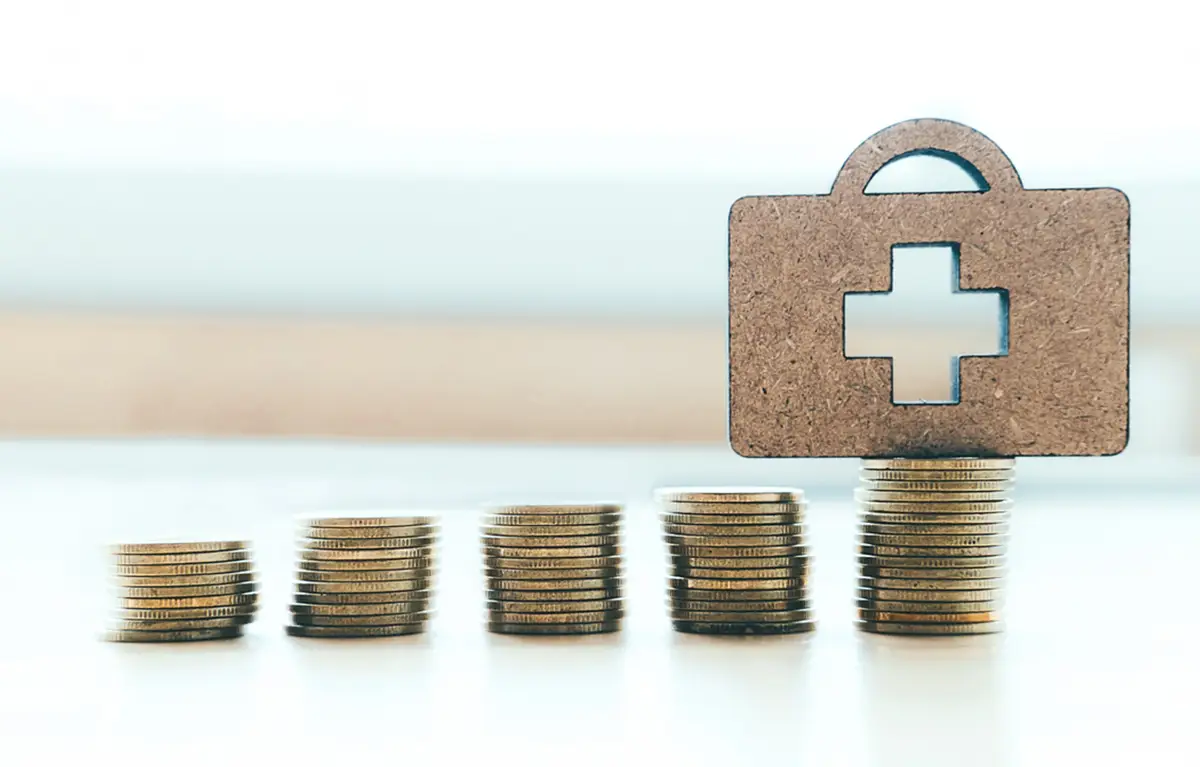 Poslagane kovanice eura u nizu, u pozadini znak križa. Koncept: zdravstvo i financije.