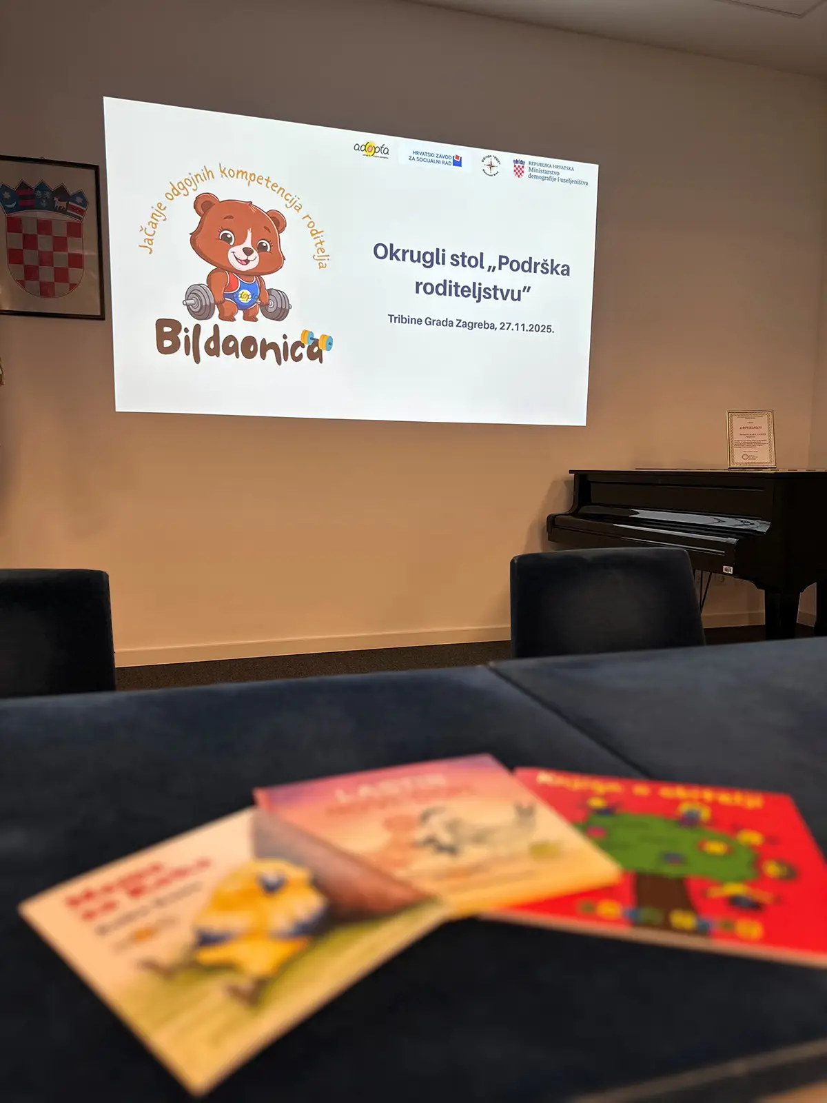 Ekran s prikazom projekta Bildaonica Udruge Adopta i letcima, na okruglom stolu Podrška roditeljstvu