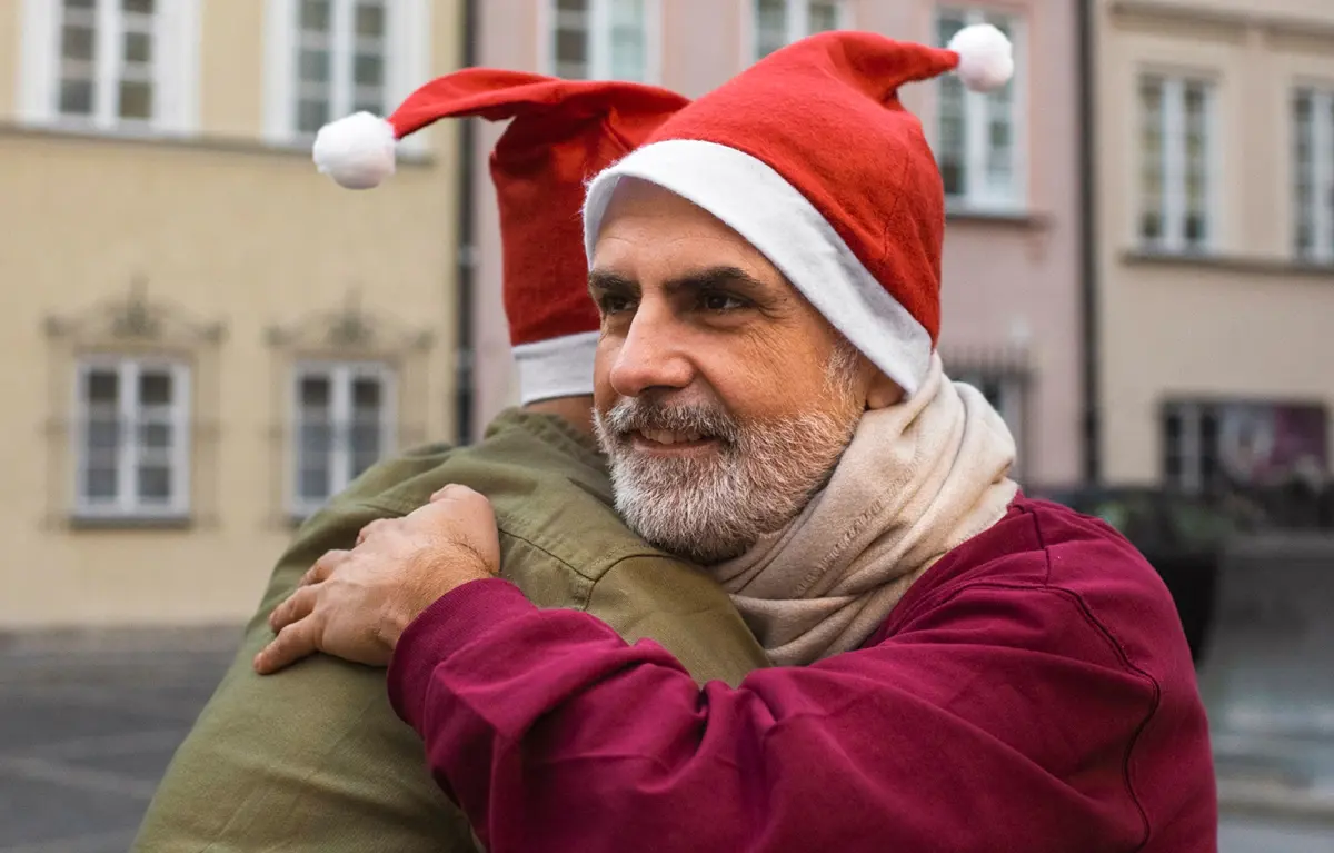 Dva muškarca s božićnim kapicama u zagrljaju; koncept pomoć za osobe s demencijom