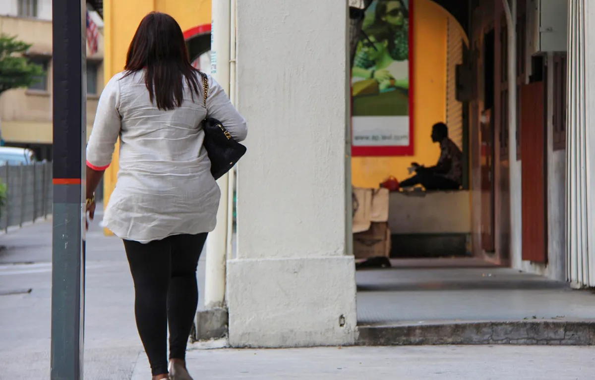 Žena okrenuta leđima šeta po ulici. Koncept: lijekovi za debljinu i tjelesna aktivnost.