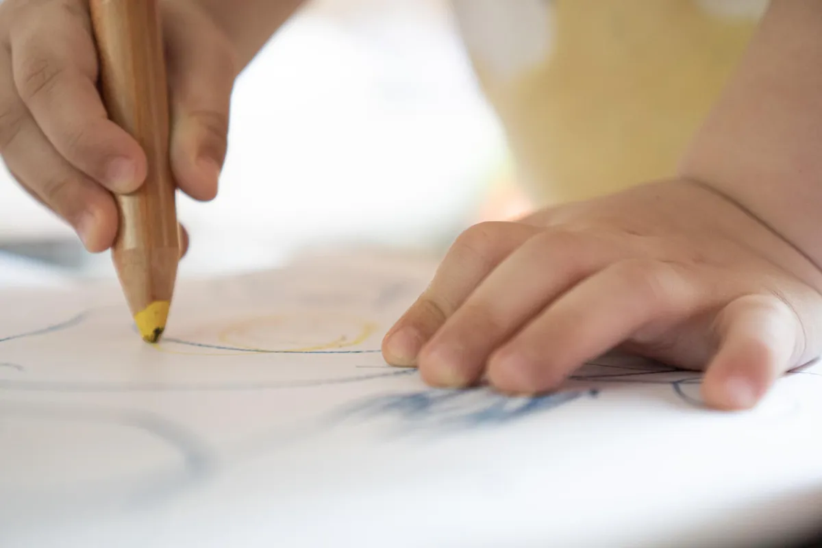 Dječja ruka crta crtež na papiru. Koncept radionice udruge Krijesnica