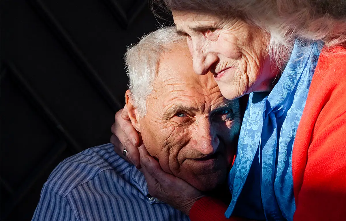 Stari bračni par u zagrljaju; briga o oboljelom od Alzheimerove bolest
