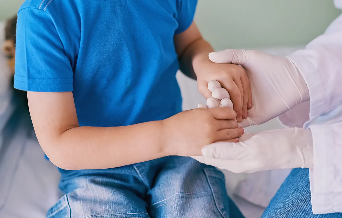 Neprepontaljivog dječaka liječnik drži za ruke u znak podrške; laser tag game i trajnja ozljeda oka