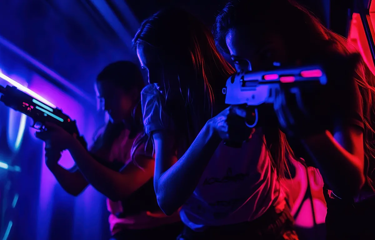 Mladi u igraonici igraju laser tag game s laserskim pištoljima; trajna ozljeda oka