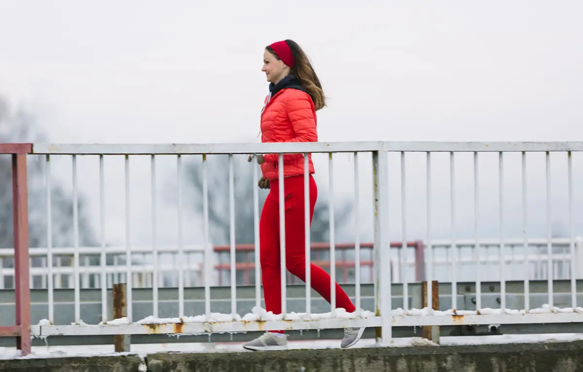 Žena obučena u crveno trči preko mosta. Koncept: moždani udar kod žena.