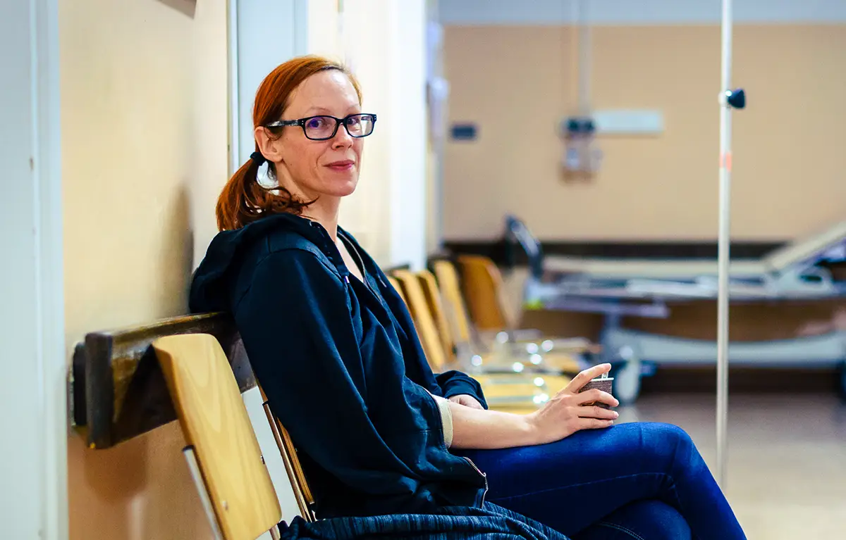 Pacijentica sjedi u bolničkoj čekaonici s kavom u ruci i gleda u kameru; komentar povodom Svjetskog dana bolesnika kakvi smo kao pacijenti