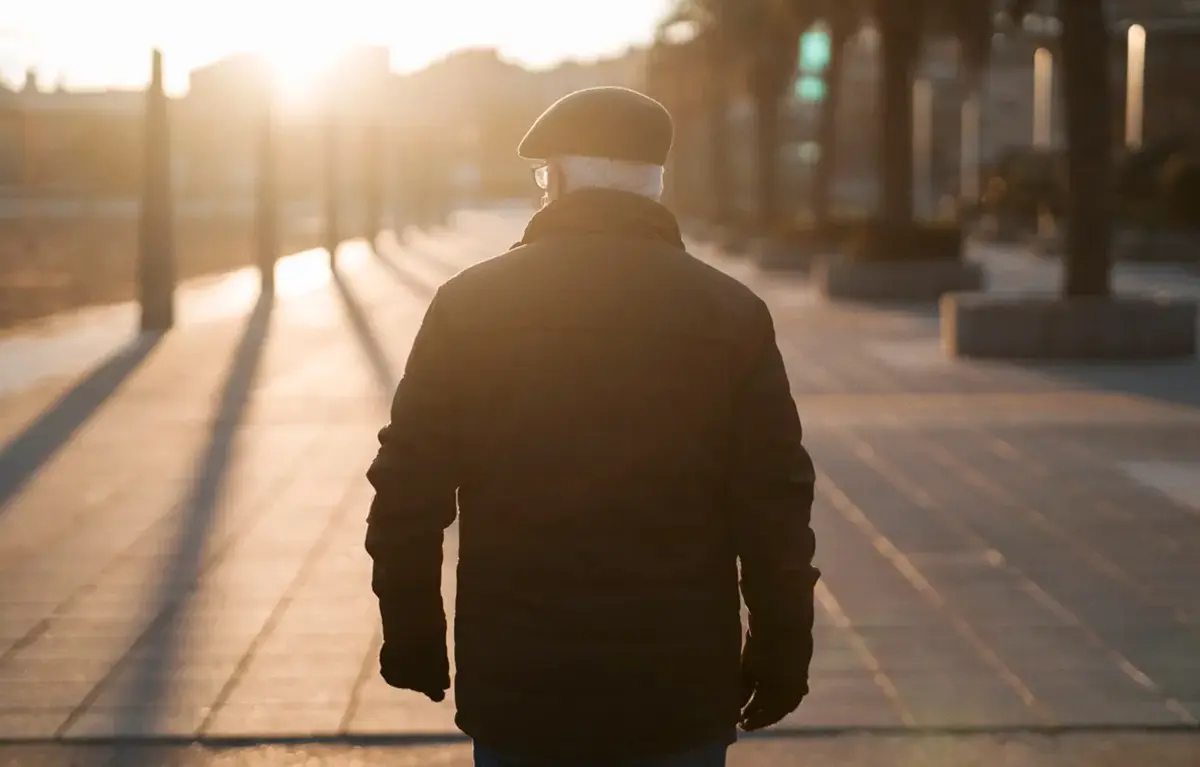 Stariji muškarac prikazan s leđa hoda ulicom u protusvjetlu; koncept preživljenje raka prostate i liječenje rak prostate