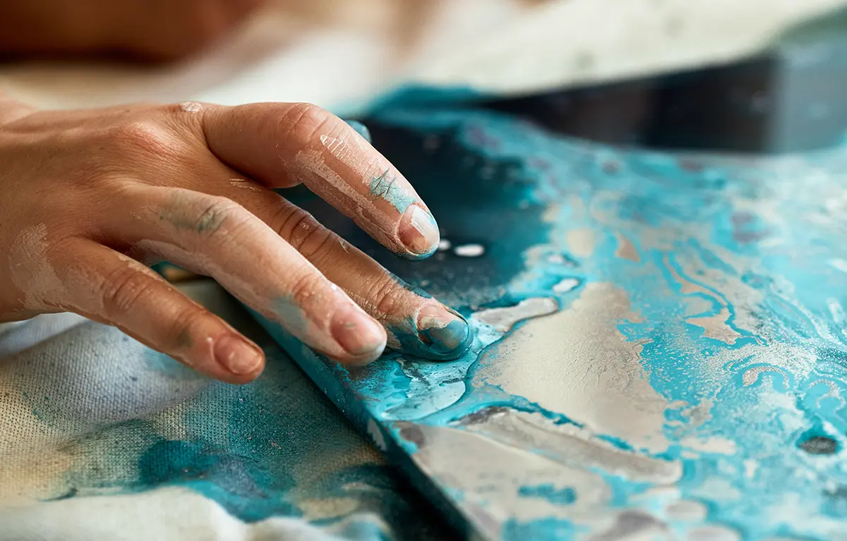 Ruka neprepoznatljive žene dotiče tirkiznu slikarsku boju razmazanu na platnu; život nakon dijagnoze raka dojke, blog autorice Sanja Kalebić