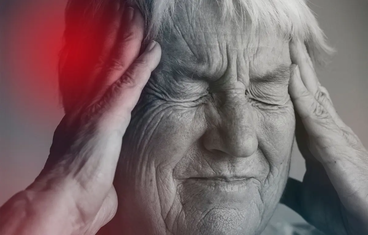 migrena-najava-Korzo Crno-bijela fotografija, starija osoba drži se za glavu objema rukama, preko jednog dijela glave crvena je boja kao indikator boli; koncept migrena i javnozdravstvena akcija na Korzu u Rijeci, Hrvatski dan migrene