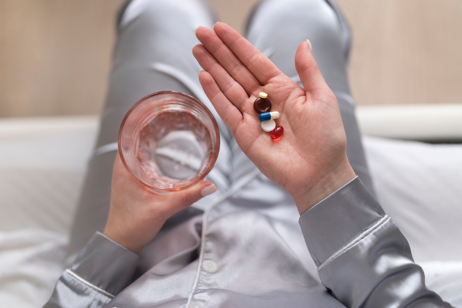 Za kortizol, hormon stresa, savjetuju se razni dodaci prehrani. Tablete na dlanu ruke i čaša vode u drugoj ruci. 