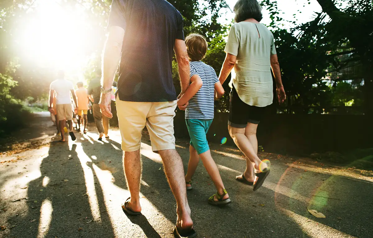Skupina ljudi različite dobi, prikazana s leđa, u šetnji prirodom; tjelovježba i psihičko zdravlje