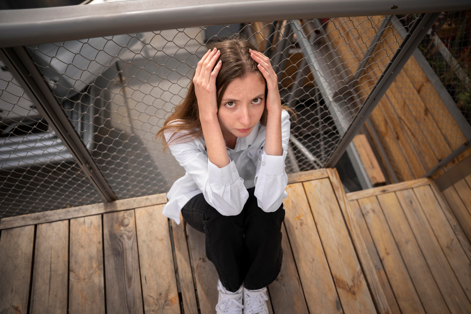 Žena sjedi na podu i rukama se drži za glavu. Koncept mindfulness tehnika u užurbanoj svakodnevnici.
