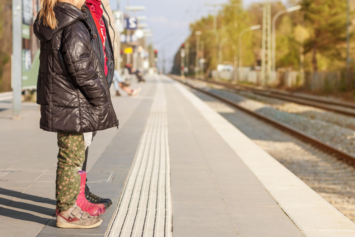 Grad po mjeri svih Djevojčica stoji uz rub pločnika uz tramvajsku prugu. Koncept: pristupačnost grada